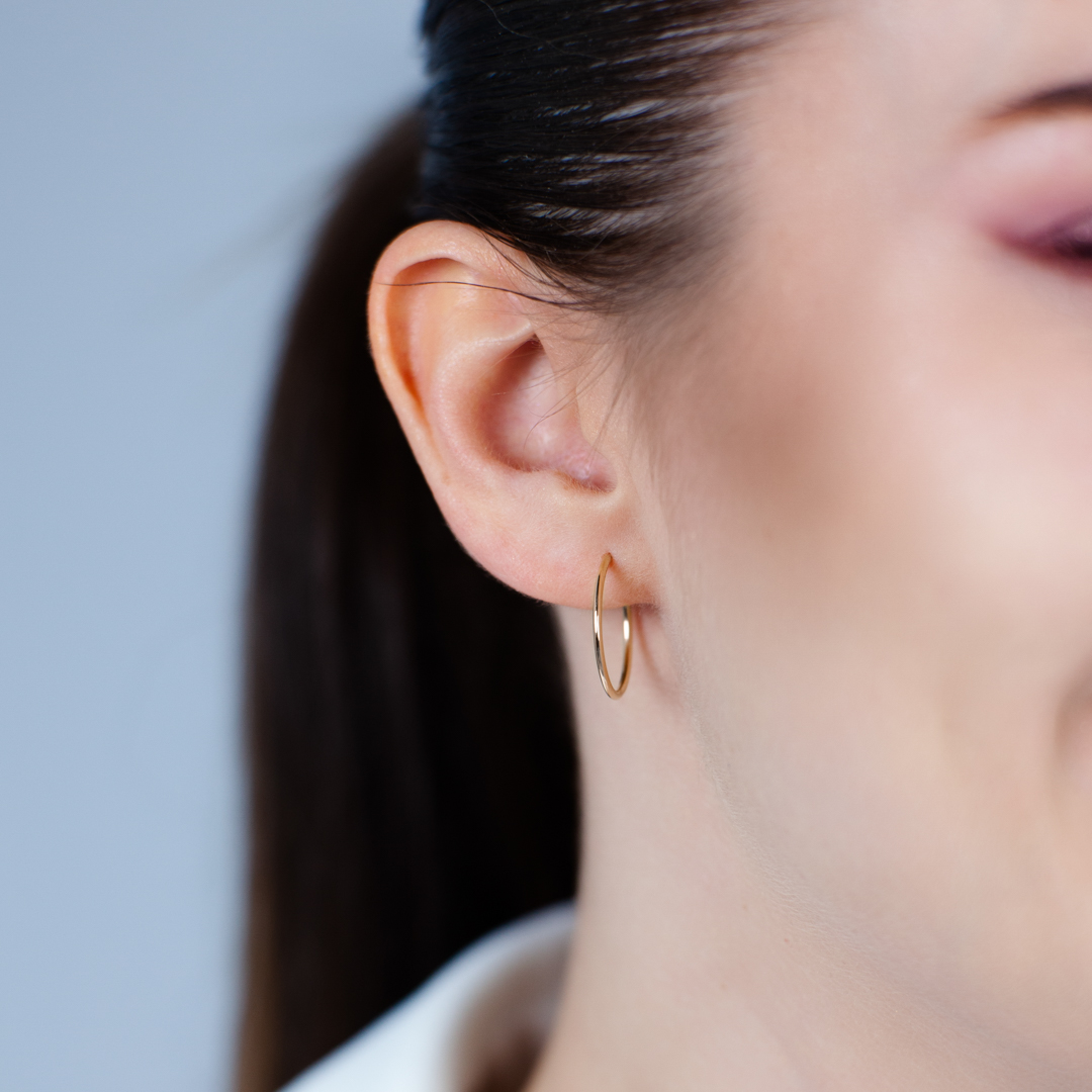 Klasické celozlaté kruhové náušnice o průměru 2 cm na uchu modelky